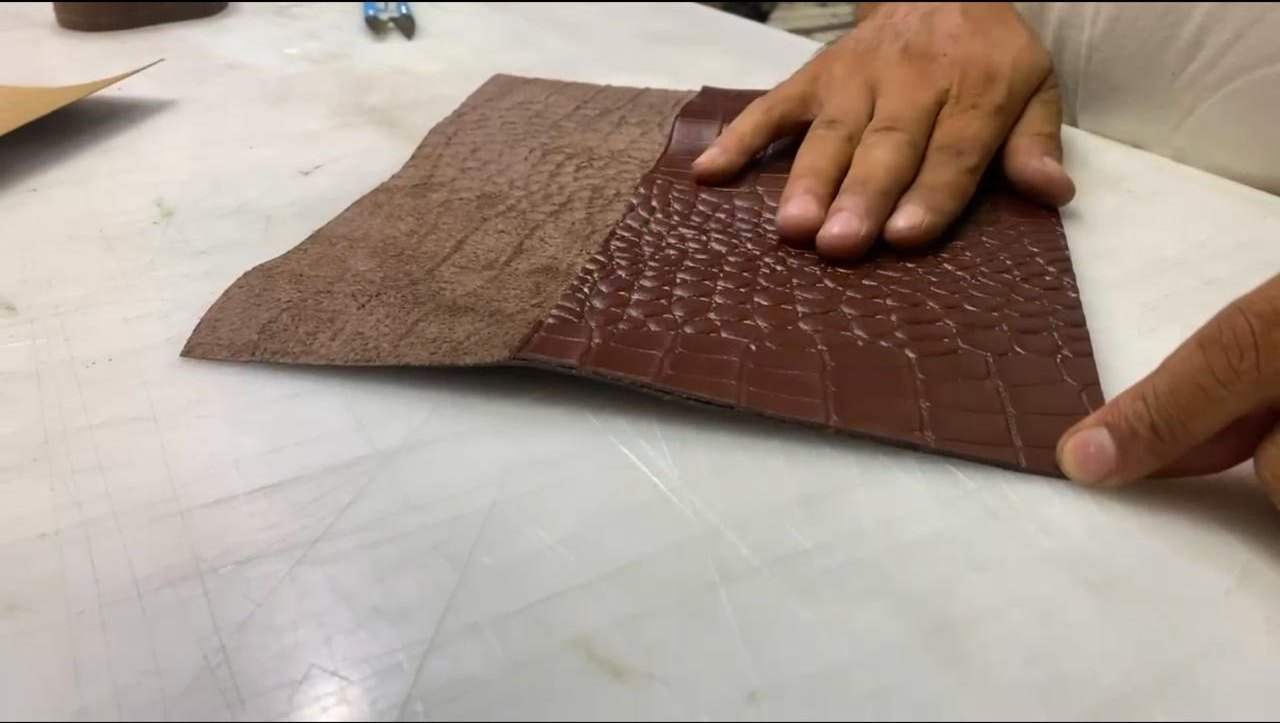 Hands inspecting embossed leather